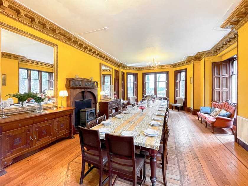 A dressed dining room in the group's Scottish house — long table, working fireplace, original cornicing.